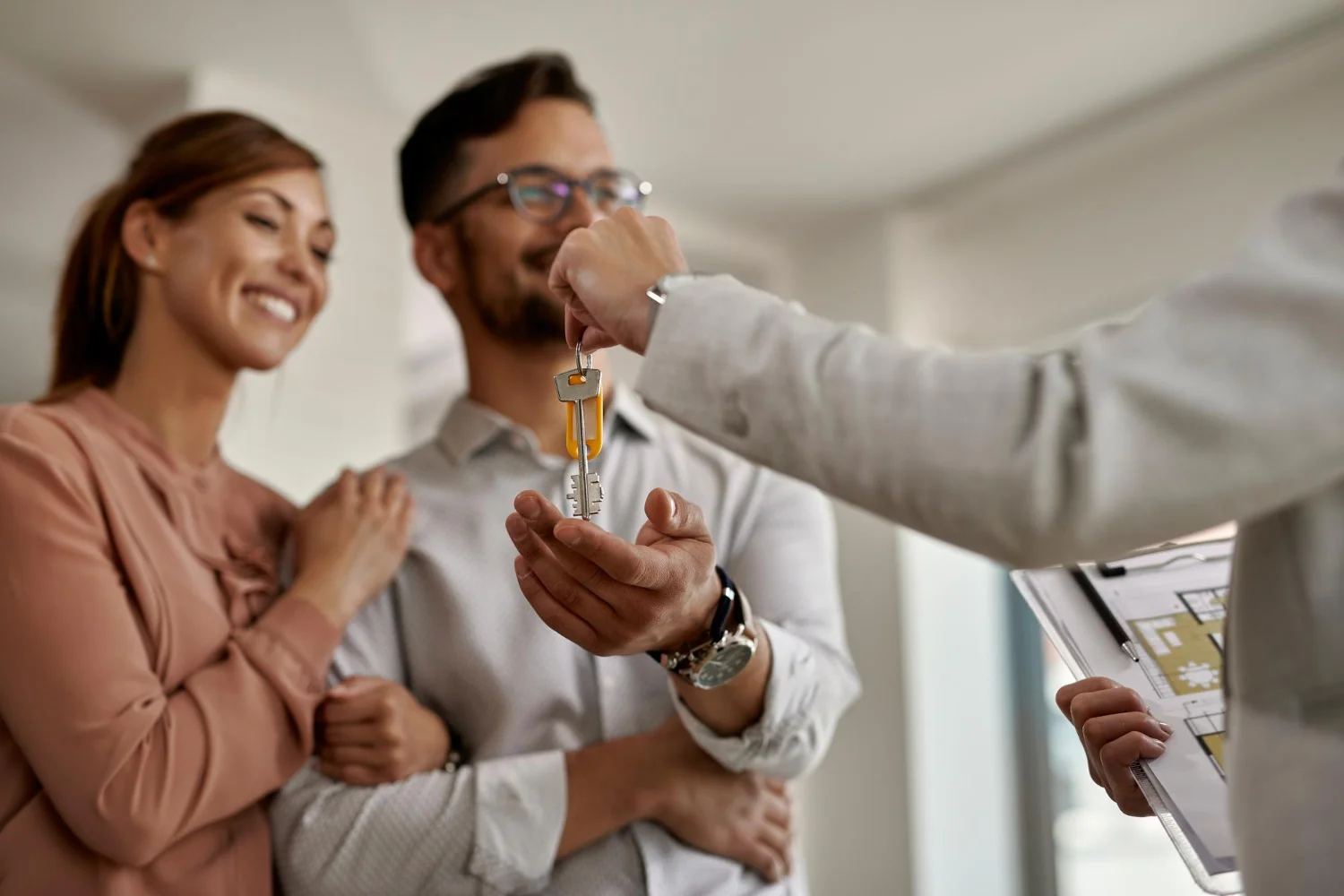 Un couple heureux reçoit les clés de leur nouvelle maison d'un agent, dans un moment qui semble marquer un nouveau départ.