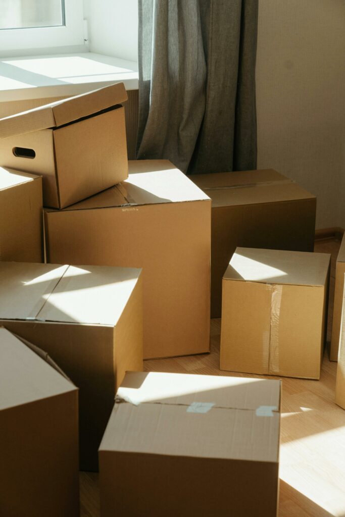 Des cartons d'emballage éparpillés dans une pièce ensoleillée, évoquant un déménagement ou le processus d'installation dans un nouvel espace de vie.