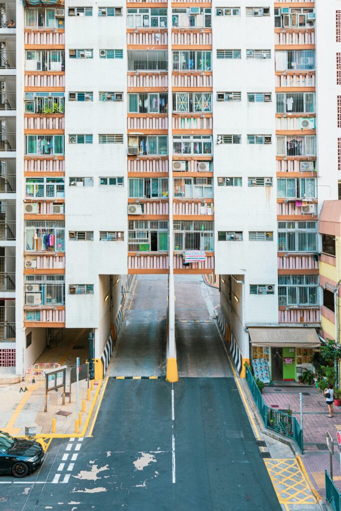 La façade d'un bâtiment résidentiel dense avec des balcons colorés s'étend de part et d'autre d'une rampe de voie d'accès, reflétant une symétrie architecturale et la vie urbaine animée.