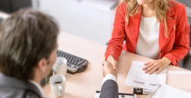 Deux professionnels se serrent la main au-dessus d'un bureau, signifiant probablement un accord ou une entente réussie.
