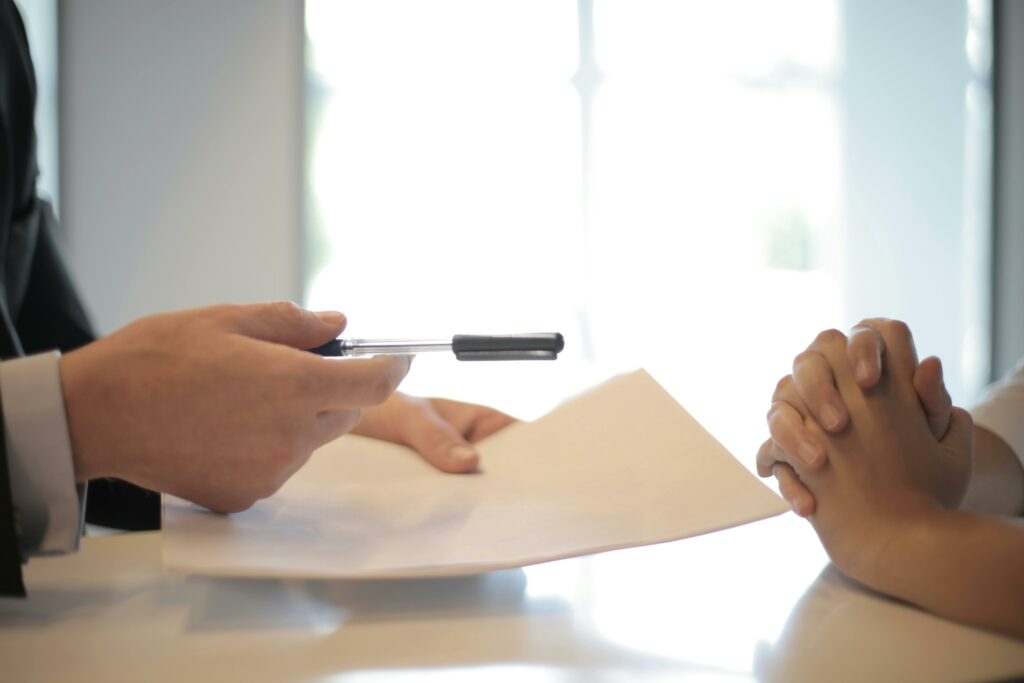 Un professionnel passe un stylo à une personne, indiquant probablement la signature d'un document important ou la finalisation d'une transaction.