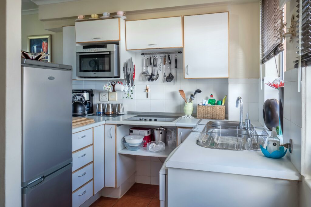 Une cuisine compacte et fonctionnelle avec des appareils électroménagers en acier inoxydable et des armoires blanches, démontrant un espace bien organisé et utilisé efficacement.