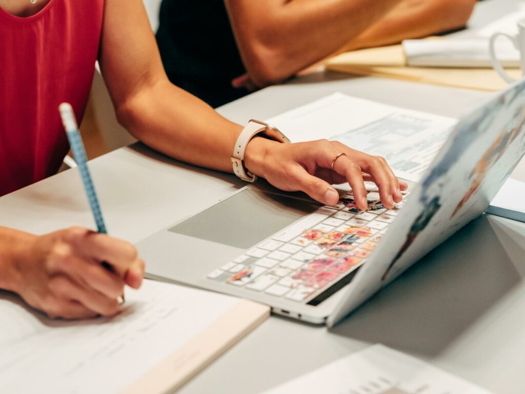 Une personne est concentrée sur son ordinateur portable, prenant des notes, ce qui suggère un travail de recherche ou une étude approfondie.