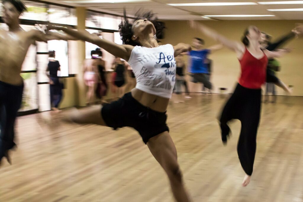Des danseurs en mouvement dans un studio de danse, le flou de l'image capturant l'énergie et le mouvement de leur activité.