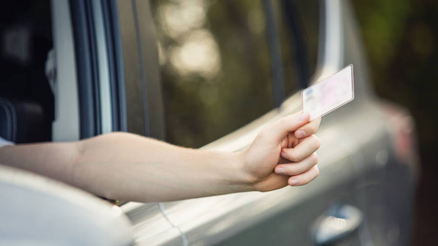 Une main sortant d'une voiture et tenant une carte de stationnement ou un ticket, un acte commun dans les situations de parking urbain