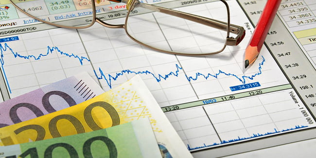 Des graphiques financiers, des lunettes et des billets de banque européens, représentant l'analyse financière ou l'investissement.
