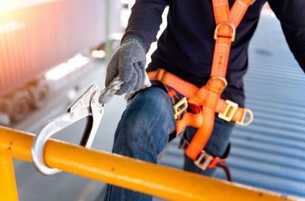 Un travailleur en équipement de sécurité est accroupi sur un toit, mettant l'accent sur la prévention des accidents dans le milieu du travail.
