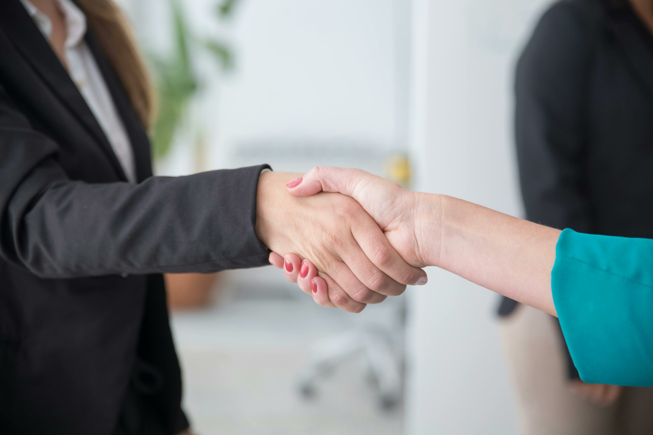 Poignée de main entre deux professionnelles dans un bureau, symbolisant un accord ou une introduction formelle.